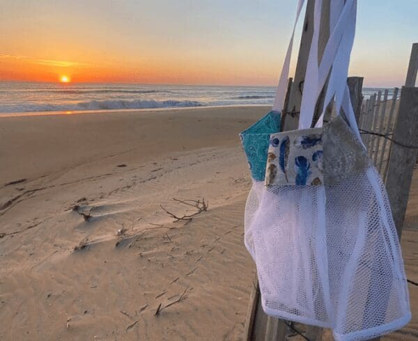 A beach bag hanging on a pole at sunset.