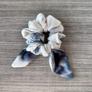 A Tie Dye Sky Blue scrunchie on a wooden surface.