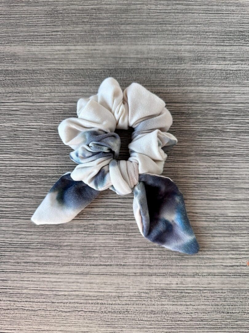 A Tie Dye Sky Blue scrunchie on a wooden surface.